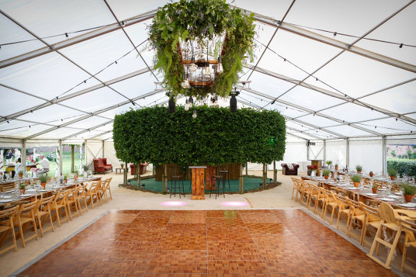 Pendant drop light in marquee dressed with fresh flowers and foliage