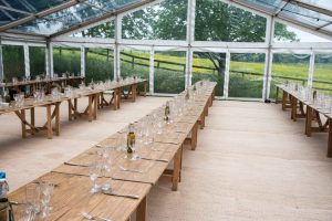 Trestle tables for rustic themed wedding in glass style marquee